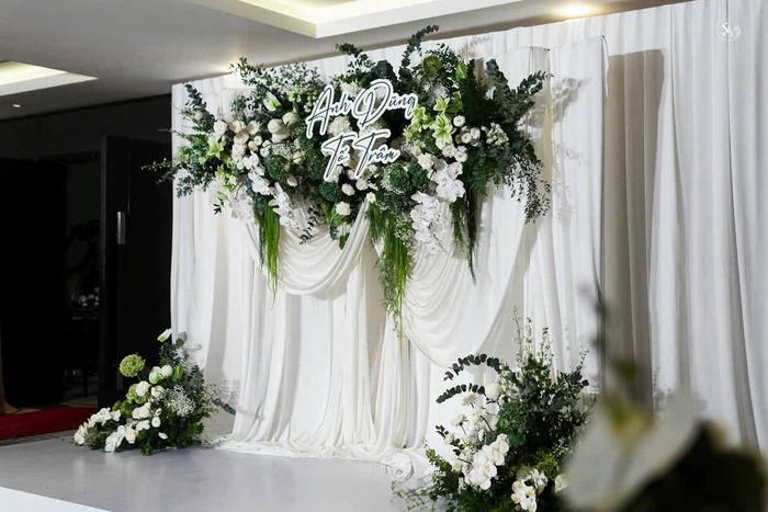 Backdrop rèm trắng phối lá xanh và chữ đèn